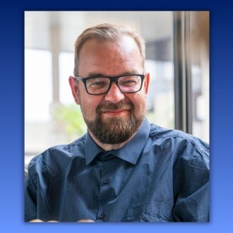Das Bild zeigt Prim. Dr. Thomas Trabi in einer Portr&auml;taufnahme. Er tr&auml;gt eine dunkle Brille sowie ein dunkelblaues Hemd und blickt mit einem freundlichen L&auml;cheln in die Kamera. 