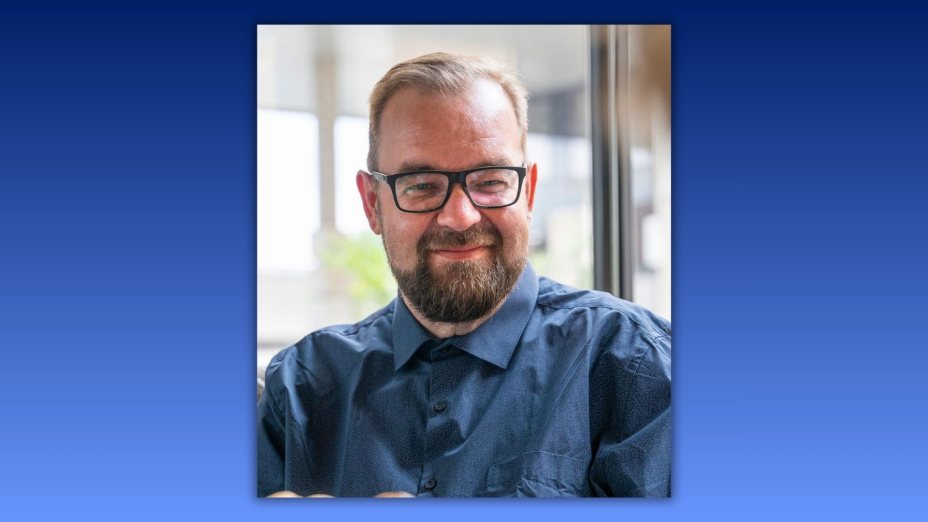 Das Bild zeigt Prim. Dr. Thomas Trabi in einer Portr&auml;taufnahme. Er tr&auml;gt eine dunkle Brille sowie ein dunkelblaues Hemd und blickt mit einem freundlichen L&auml;cheln in die Kamera. 