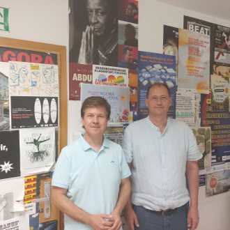Auf dem Bild stehen zwei M&auml;nner nebeneinander in den R&auml;umlichkeiten von Radio AGORA.