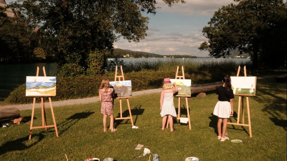 Kinder mit Staffeleien beim Malen auf einer Wiese